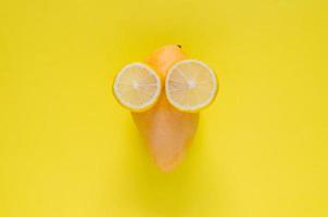 maturo giallo mango e fetta di limoni impostato come viso con occhi su giallo sfondo. minimo estate concetto. foto
