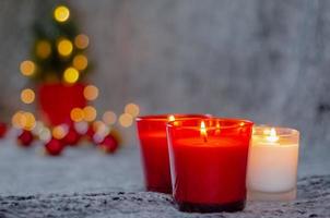 messa a fuoco e sfocato di ardente candele nel rosso e bianca bicchiere con bokeh leggero di Natale albero sfondo. foto