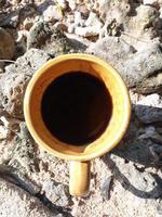 un' tazza di nero caffè nel un' Marrone tazza, su il spiaggia sabbia foto