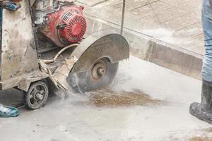 lavoratore utilizzando diamante sega lama macchina taglio calcestruzzo strada a costruzione luogo foto