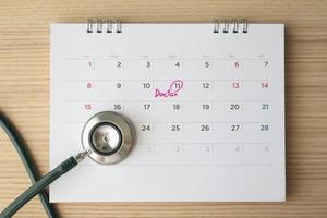 stetoscopio con calendario pagina Data su legna tavolo sfondo medico appuntamento medico concetto foto