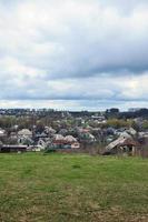 un' rurale paesaggio con molti privato case e verde alberi. suburbano panorama su un' nuvoloso pomeriggio. un' posto lontano a partire dal il città foto