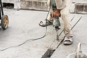 costruzione lavoratore utilizzando martello pneumatico perforazione calcestruzzo superficie foto