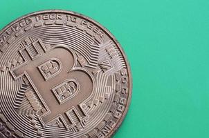 cioccolato Prodotto nel il modulo di fisico bitcoin bugie su un' verde plastica sfondo. modello di il crypto moneta nel il commestibile modulo foto