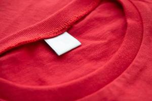 bianca vuoto capi di abbigliamento etichetta etichetta su nuovo rosso cotone camicia tessuto struttura sfondo foto