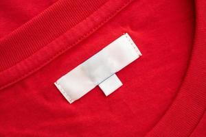bianca vuoto capi di abbigliamento etichetta etichetta su nuovo rosso cotone camicia tessuto struttura sfondo foto