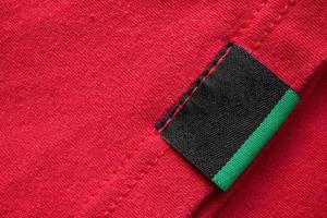 nero vuoto lavanderia cura Abiti etichetta su rosso cotone camicia sfondo foto