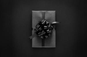 un' nero regalo scatola con nastro e prezzo etichetta mette su nero sfondo. nero Venerdì e boxe giorno concetto. foto