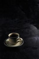 un' tazza di caldo caffè su un' nero sfondo. buio scena. bandiera spazio modello per aggiungendo testo foto