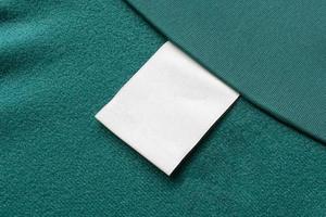 vuoto bianca lavanderia cura Abiti etichetta su verde tessuto struttura sfondo foto