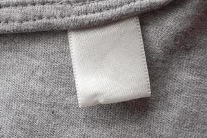 vuoto bianca lavanderia cura Abiti etichetta su grigio tessuto struttura sfondo foto