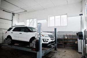 auto suv americana su cavalletto per allineamento ruote camber check in officina della stazione di servizio. foto