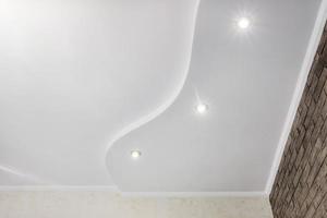 dettaglio di angolo soffitto con intricato corona modanatura. sospeso soffitto e cartongesso costruzione nel vuoto camera nel appartamento o Casa. allungare soffitto bianca e complesso forma. foto