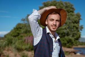 giovane uomo nel un' cappello su natura sembra per il lato foto