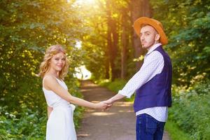 il ragazza detiene mani con un' uomo su il sfondo di il sentiero nel il foresta. foto