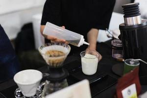 barista misurazione latte e sciroppo preparare fabbricazione ghiacciato caffè latte macchiato. foto