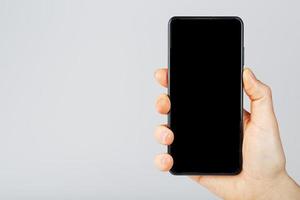 il mano detiene un' nero smartphone con un' vuoto nero schermo e un' moderno frameless design foto