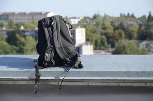 nero zaino bugie su metallo confine di residenziale multipiano edificio tetto nel soleggiato tempo metereologico foto