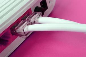 il Internet cavo spine siamo collegato per il Internet router, quale bugie su un' luminosa rosa sfondo. elementi necessario per Internet foto