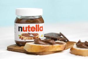 Kharkov, Ucraina - dicembre 27, 2020 Nutella bicchiere può e diffusione su appena al forno pane. Nutella è manufatto di italiano azienda ferrero primo introdotto nel 1964 foto