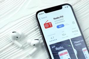 Kharkov, Ucraina - marzo 5, 2021 Radio fm icona e applicazione a partire dal App memorizzare su i phone 12 professionista Schermo schermo con airpods professionista su bianca tavolo foto