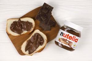 Kharkov, Ucraina - dicembre 27, 2020 Nutella bicchiere può e diffusione su appena al forno pane. Nutella è manufatto di italiano azienda ferrero primo introdotto nel 1964 foto