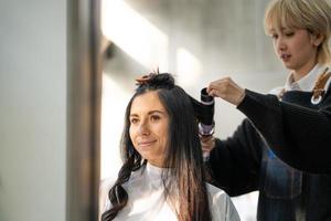 caucasico donne con capelli elegante mentre fare capelli tagliare e indossare chirurgico viso maschera mentre messa in piega capelli per cliente. professionale occupazione, bellezza e moda servizio nuovo normale foto