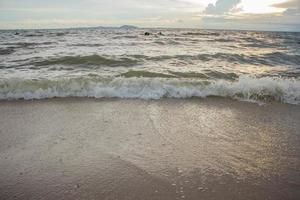 il spiaggia il mare dove il onde siamo colpire il riva sotto il bellissimo cielo il sole è andando giù foto