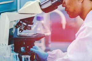 asiatico maschio medico o scientifico ricercatore o medico utilizzando guardare a un' chiaro soluzione nel un' laboratorio. foto