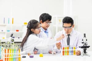 selettivo messa a fuoco a ragazzo viso. giovane asiatico ragazzo e ragazza studia scienza classe utilizzando microscopio e chimico liquido per fare il sperimentare dentro laboratorio. formazione scolastica concetto. foto