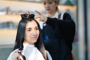 caucasico donne con capelli elegante mentre fare capelli tagliare e indossare chirurgico viso maschera mentre messa in piega capelli per cliente. professionale occupazione, bellezza e moda servizio nuovo normale foto