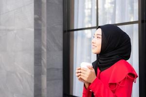 bellissimo est asiatico islamico donne indossare hijab con formale vestire. Tenere caffè tazza e a piedi nel urbano città la zona, sensazione contento e Sorridi. persone stile di vita concetto con copia spazio. foto