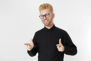 ragazzo alla moda felice in camicia nera e occhiali che puntano lo spazio della copia. concetto di imprenditore giovane di successo. uomo dai capelli rossi con la barba rossa. start up, concetto di giovane fondatore isolato su sfondo bianco foto