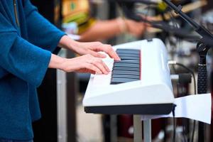 musicista donna che suona sul pianoforte della tastiera del sintetizzatore, le mani premono i tasti del sintetizzatore sul palco del concerto foto
