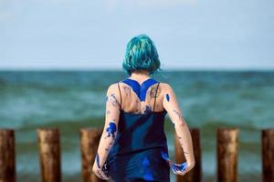 artista di performance artistica donna dai capelli blu in abito imbrattato con pitture a guazzo blu sul suo corpo foto