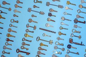 chiavi impostate su sfondo blu. chiavi della serratura e cassaforte per la sicurezza della proprietà e la protezione della casa. diversi tipi di chiavi antiche e nuove. foto