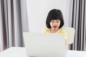 poco asiatico ragazza alunno studia in linea utilizzando il computer portatile computer a casa foto