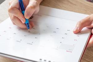 donna mano con penna scrittura su calendario Data attività commerciale pianificazione appuntamento incontro concetto foto