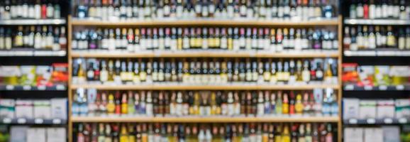 astratto sfocatura vino bottiglie su liquore alcool scaffali nel supermercato memorizzare sfondo foto