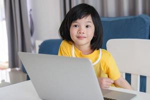 poco asiatico ragazza alunno studia in linea utilizzando il computer portatile computer a casa foto