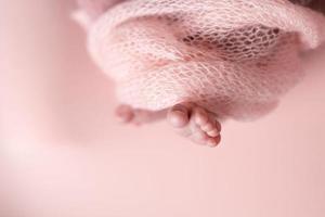 neonato bambino piedi su un' rosa sfondo avvolto nel un' a maglia coperta