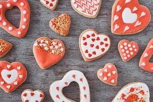 sfondo di decorato con glassatura e smaltato cuore forma biscotti su il grigio sfondo, piatto posizione. san valentino giorno cibo concetto foto