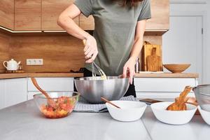 donna nel cucina cucinando un' torta. mani battere il Impasto con miscelatore foto