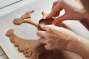 fabbricazione Pan di zenzero biscotti nel il forma di un' cuore per san valentino giorno. donna mano uso biscotto taglierina. vacanza cibo concetto foto