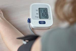 donna misurazione sangue pressione con un elettrico digitale tenere sotto controllo. assistenza sanitaria e medicina concetto foto