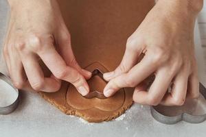 fabbricazione Pan di zenzero biscotti nel il forma di un' cuore per san valentino giorno. donna mano uso biscotto taglierina. vacanza cibo concetto foto