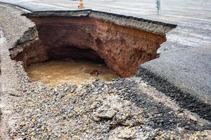 il strada era distrutto di acqua erosione causato di pesante pioggia e allagamento il strada. foto