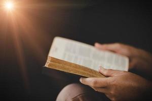 giovane donna persona mano Tenere santo Bibbia con studia a casa. adulto femmina cristiano lettura libro nel Chiesa. ragazza apprendimento religione spiritualità con pregare per Dio. concetto di alunno formazione scolastica fede. foto