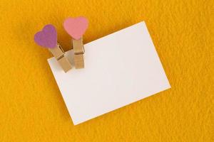 bianca foglio con rosa e viola perni su il giallo sfondo per San Valentino giorno. copia spazio. foto