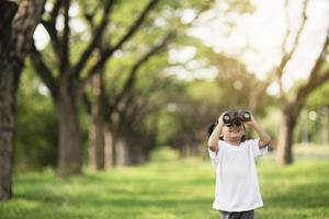 contento bambino ragazza giocando con binocolo. Esplorare e avventura concetto foto